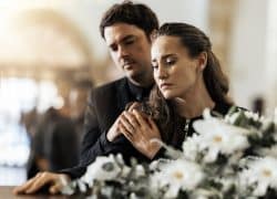 Grieving couple in front of white flowers.