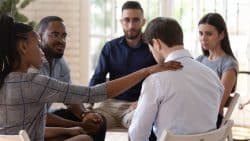 A man being comforted by a group of friends.