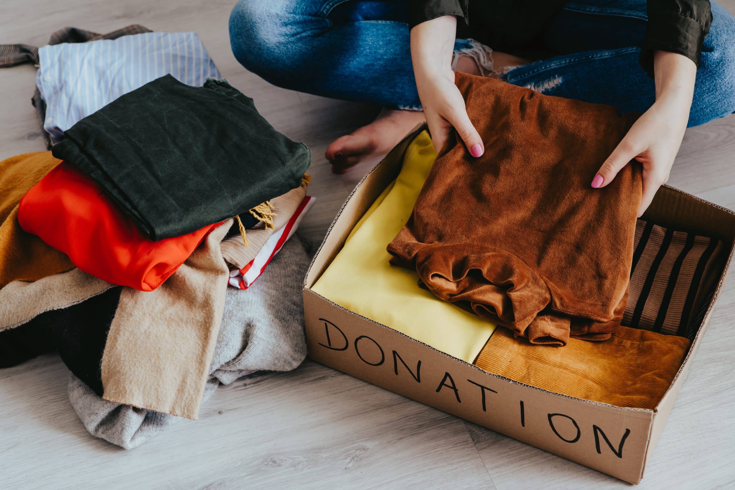 Woman packing a box marked "donations" full of clothes.