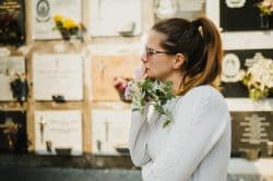 Mourning woman standing next to a columbarium wall.