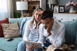 Sad people wathcing a virtual funeral service on their tablet.